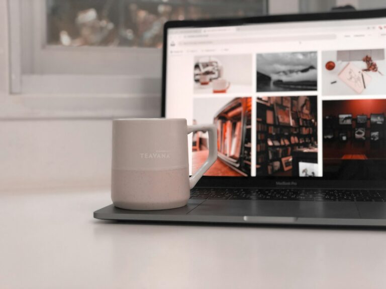 white ceramic mug beside black laptop computer